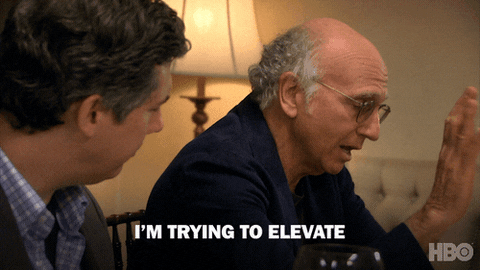 Elevate Season 8 GIF by Curb Your Enthusiasm – FSM – Digital Marketing Agency Two men sit at a table; the older man with glasses gestures as he speaks, with the caption “I'M TRYING TO ELEVATE.”