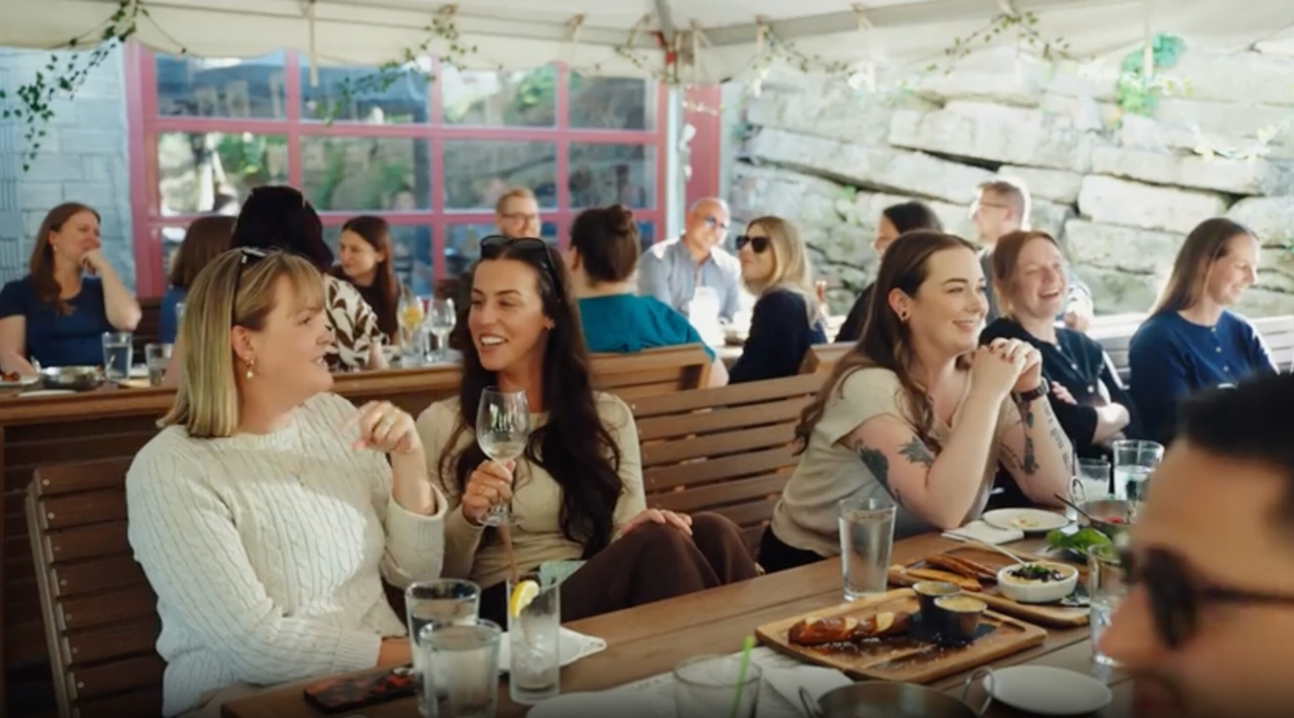 A scene from an outdoor patio and the FSM team is smiling, laughing, and enjoying beverages and appetizers