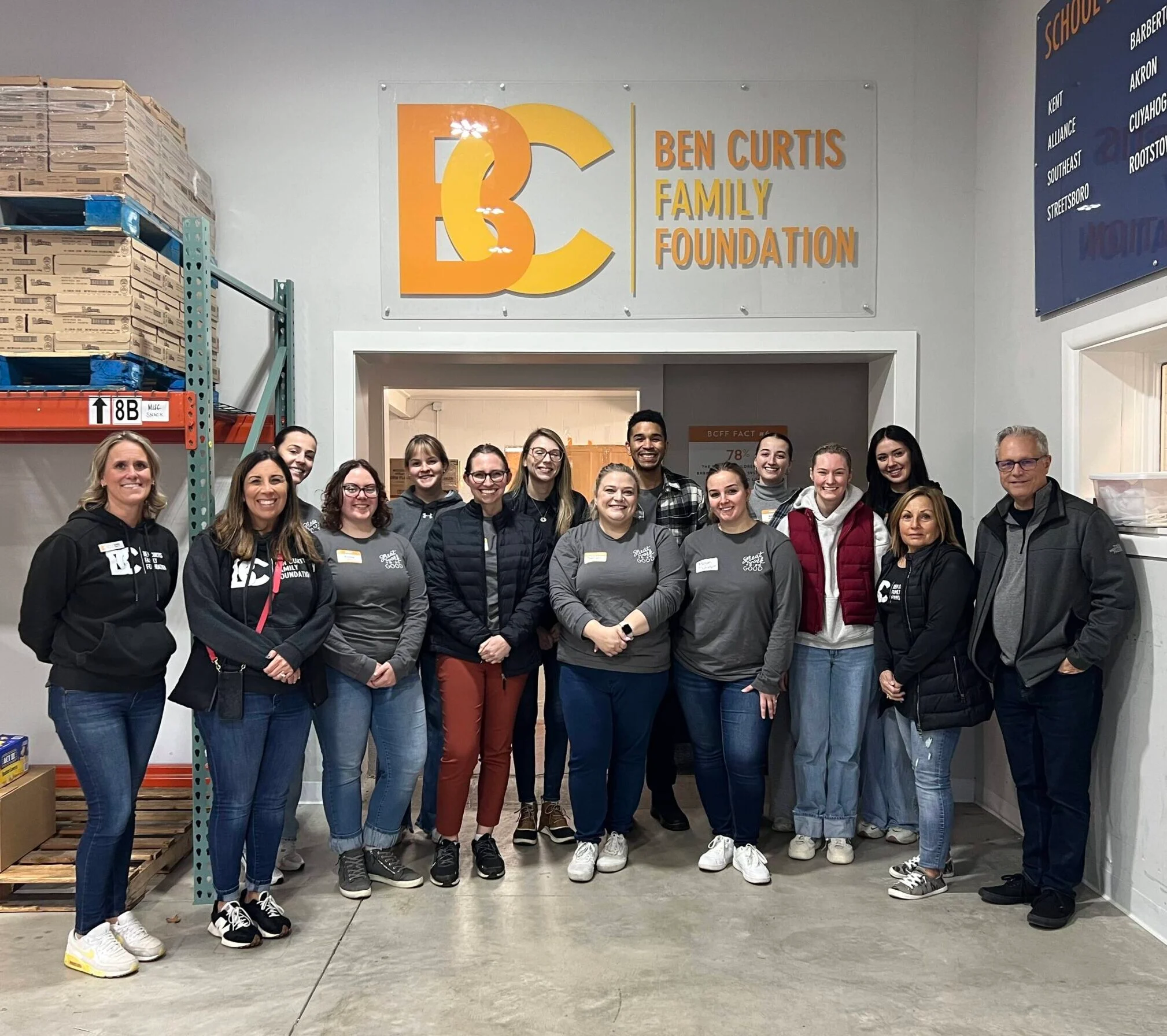 Teammates stand together posing at a volunteer event for the Ben Curtis Family Foundation.
