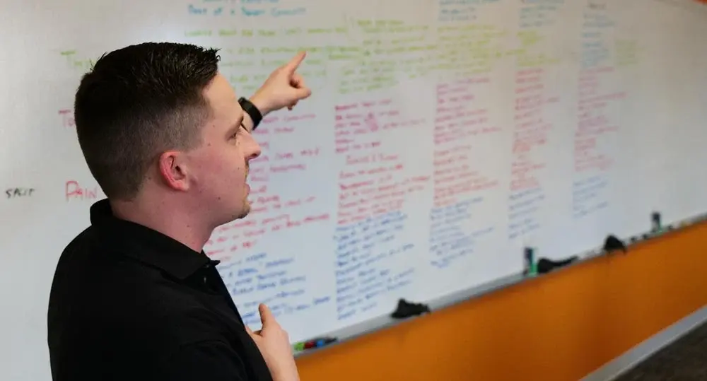 justin-journey-map-whiteboard 1 Justin points to a whiteboard during a Journey Map session.